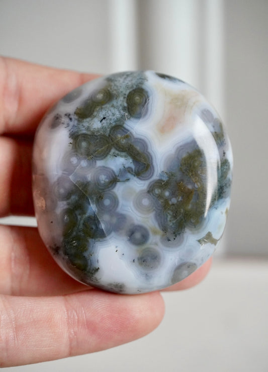 8th vein ocean jasper palm stone with white background and grey/brown orbing 